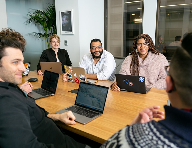Group of people at table all on laptops