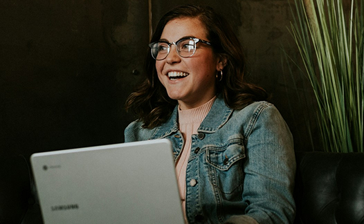 Woman with glasses staring up from laptop
