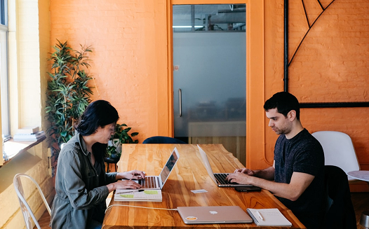 Woman and man at table with laptops